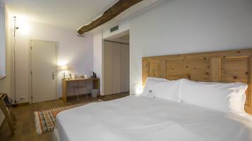 A bedroom with a large bed, a wooden headboard, a desk with a chair, and a small rug.