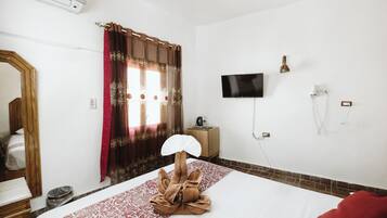 Una habitación de hotel con una cama, televisor, secador de pelo y espejo.