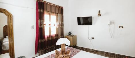 A hotel room with a bed, a TV, a hairdryer, and a mirror.