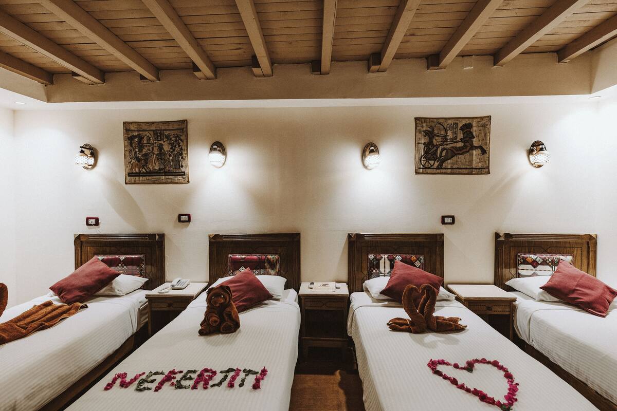 A hotel room with two beds, wooden headboards, and decorative wall sconces.