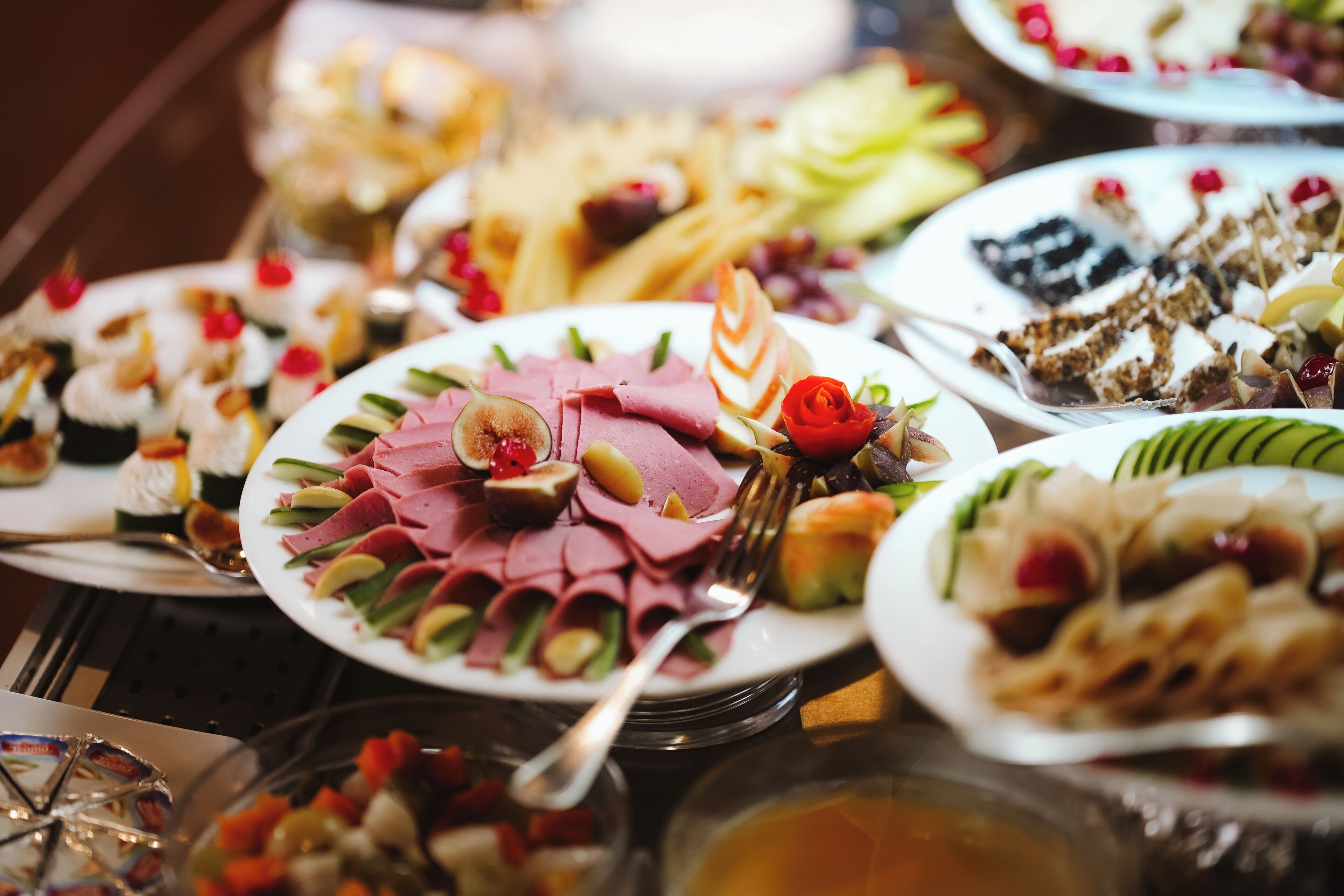 A variety of food items on a buffet table, including meats, fruits, and desserts.