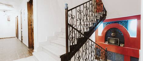 A staircase with ornate black railings leading to a landing with a red and blue decorative wall.