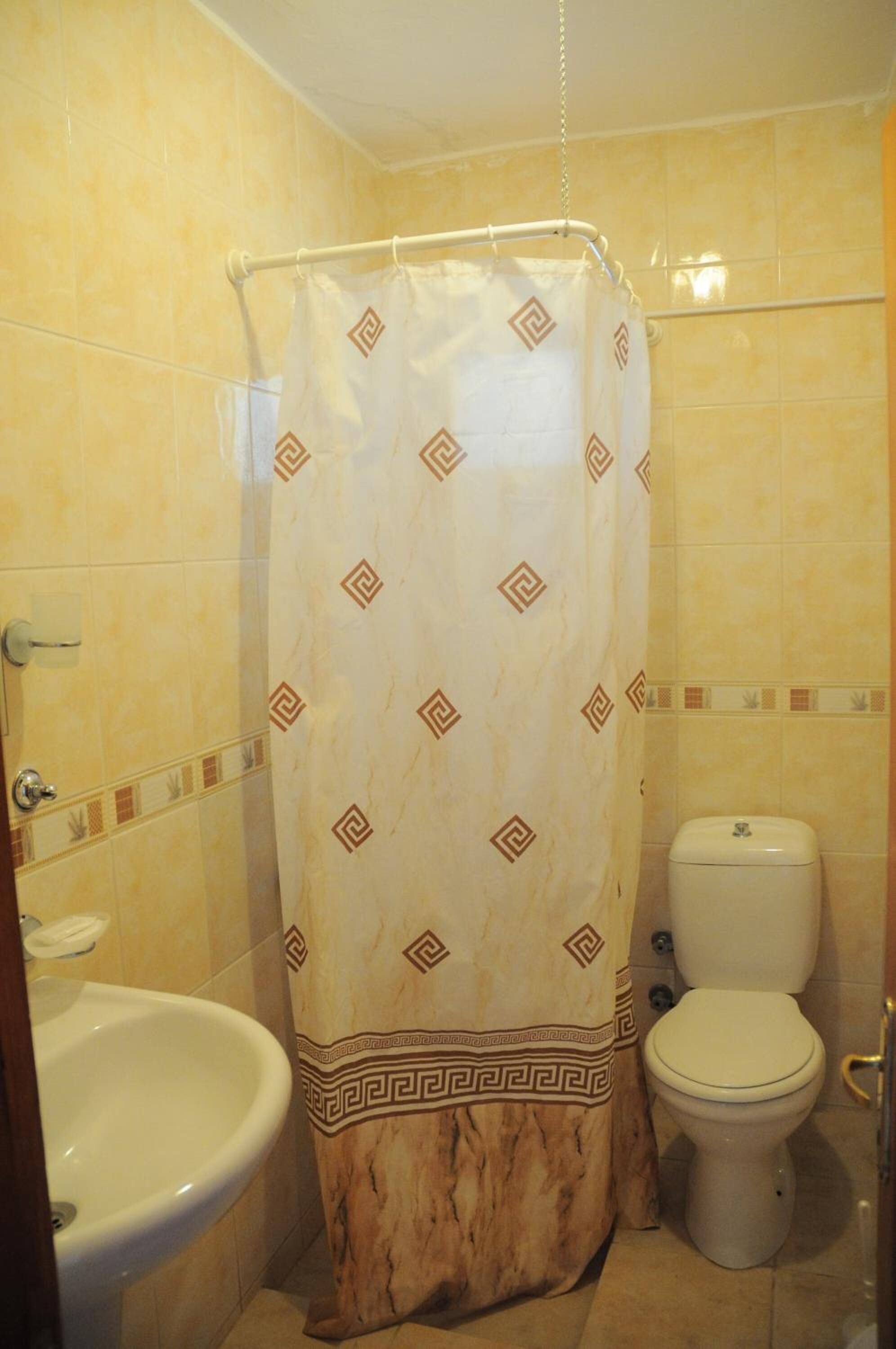 A bathroom with a shower curtain, a toilet, and a sink.