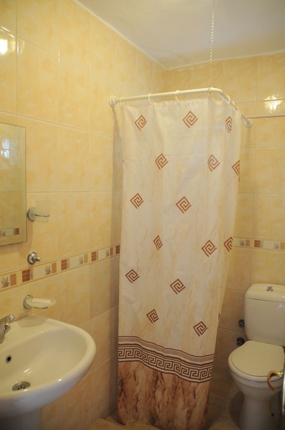 A bathroom with a shower curtain, a sink, and a toilet.