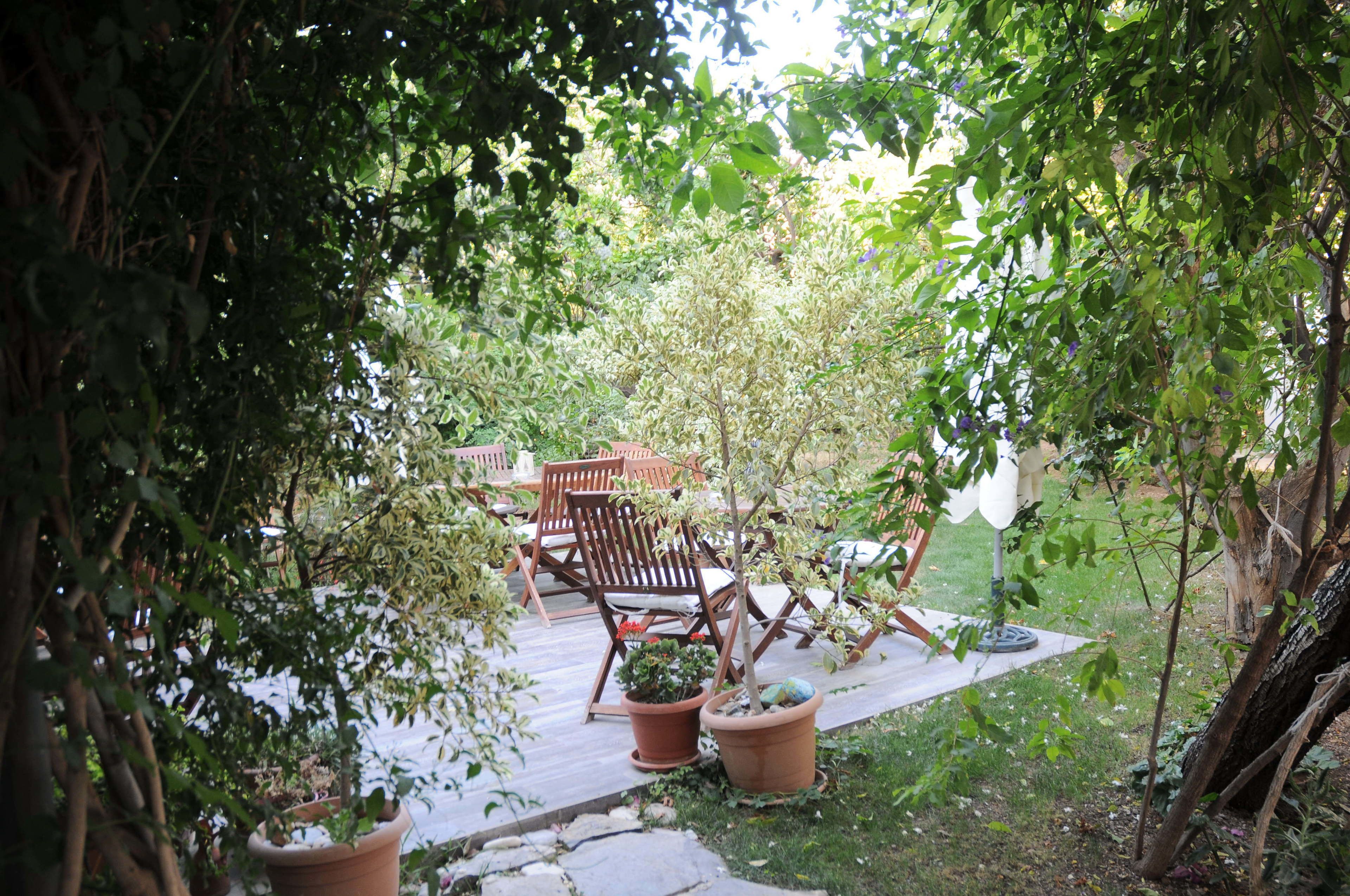 Un espace patio aménagé avec des chaises en bois et des plantes en pot, entouré de verdure.