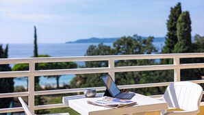 A balcony with a laptop, a cup, and a magazine, overlooking a scenic view of the sea and distant land. - Cap Nègre Hôtel (Le Lavandou)