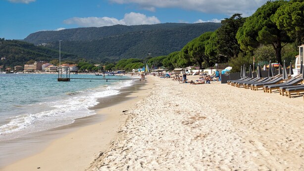 A beach with sun loungers, a pier, and mountains in the background. - Cap Nègre Hôtel (Le Lavandou)