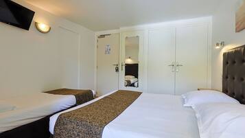A hotel room with two beds, a flat-screen TV, a mirror, and a wardrobe.