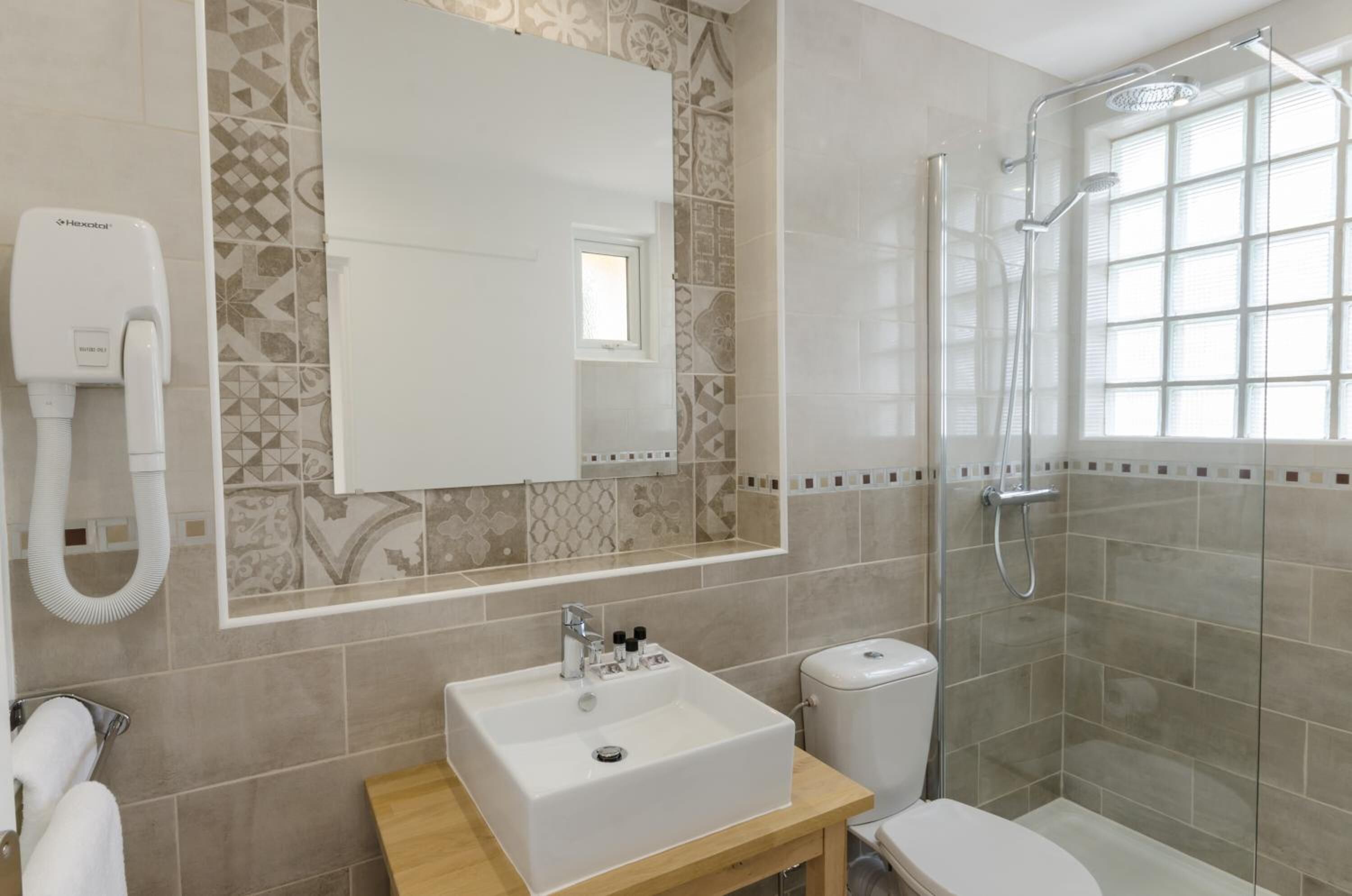 A modern bathroom with a large mirror, a sink, a toilet, and a shower.