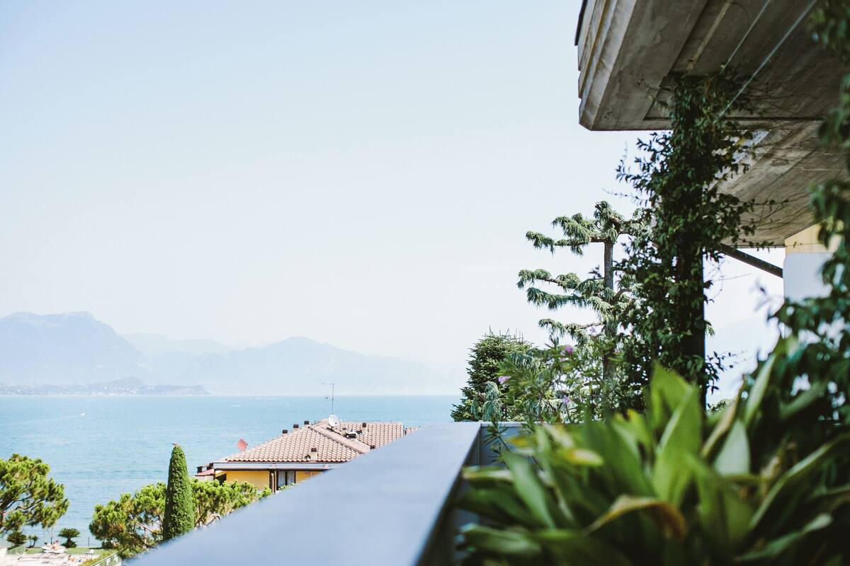 Ein Küstenblick mit einem Gebäude, das auf das Meer und die Berge blickt.