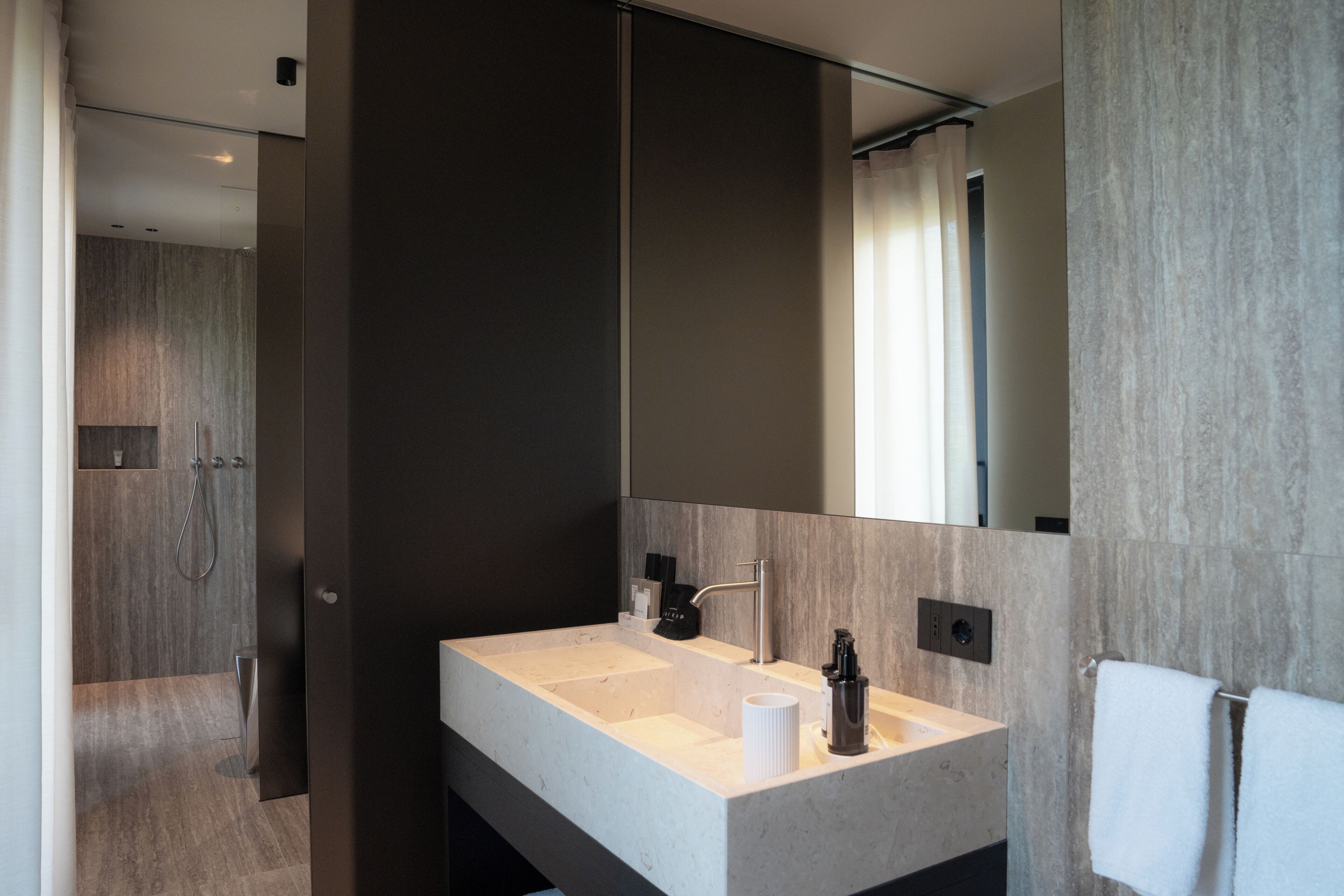 Une salle de bain moderne avec un grand miroir, un lavabo et un espace douche.