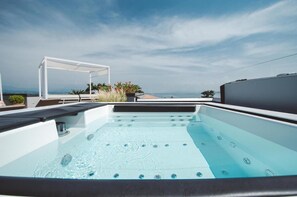 Ein Whirlpool auf dem Dach mit freiem Blick auf das Meer und einer weißen Pergola.