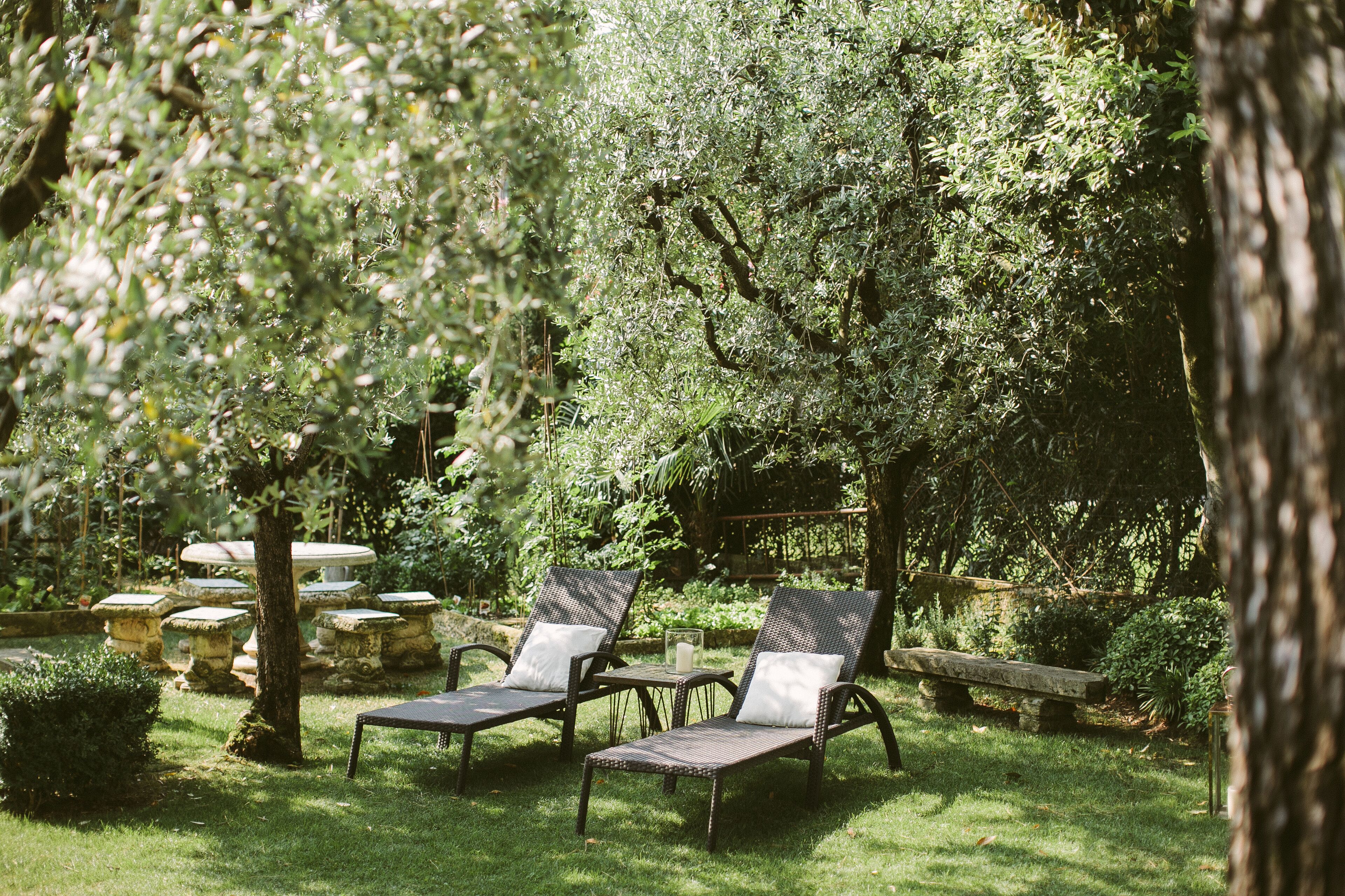 Ein Garten mit zwei Liegestühlen, einem Steintisch und einer Steinsitzbank.