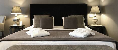 A neatly made bed with two pillows, a bedside table with a lamp, and a chair.