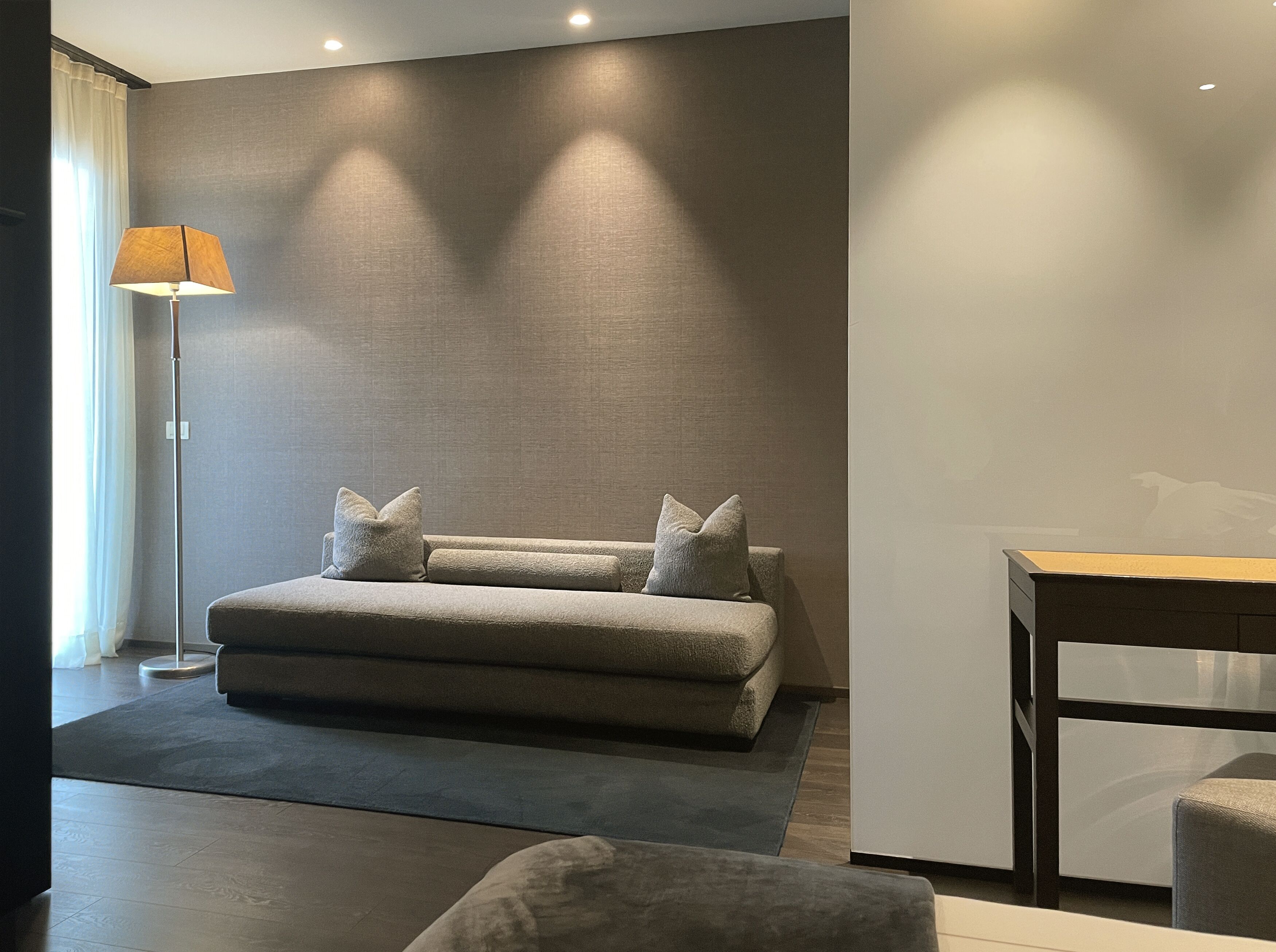 A modern living room with a sofa, a lamp, and a small table.