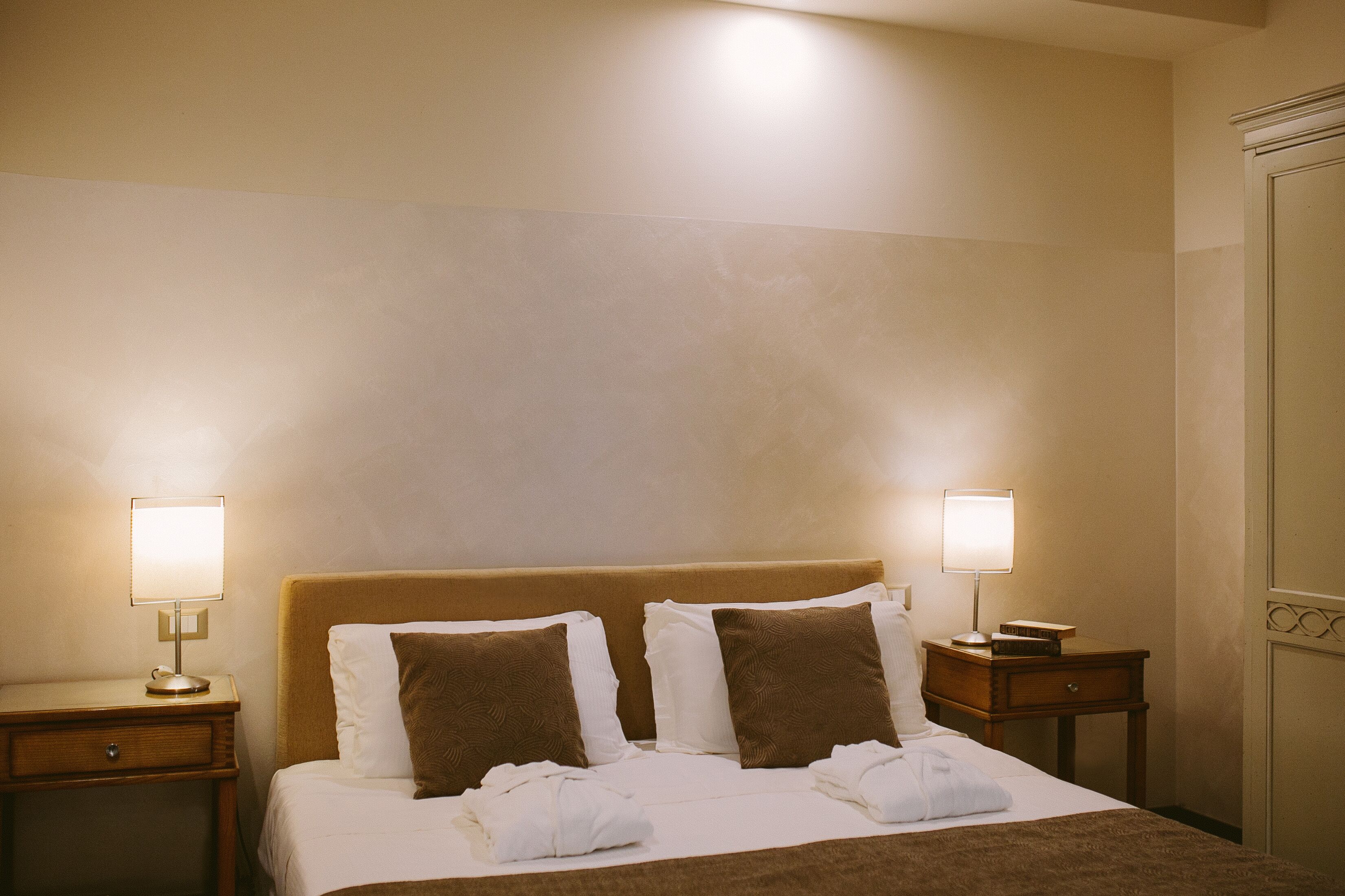 Une chambre d’hôtel avec un lit, deux tables de chevet et deux lampes.