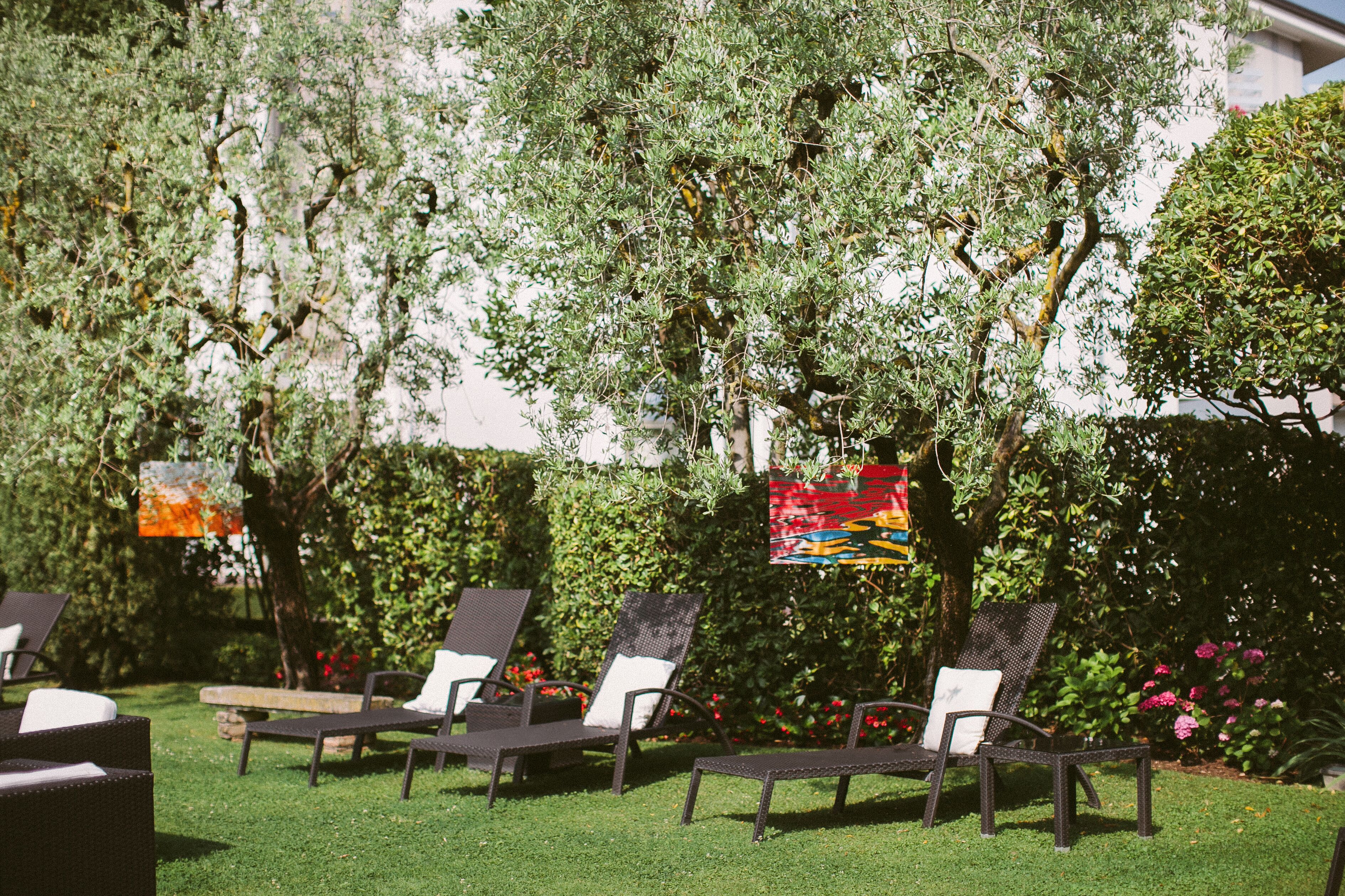 Outdoor seating with chairs and tables, surrounded by greenery and a wall.