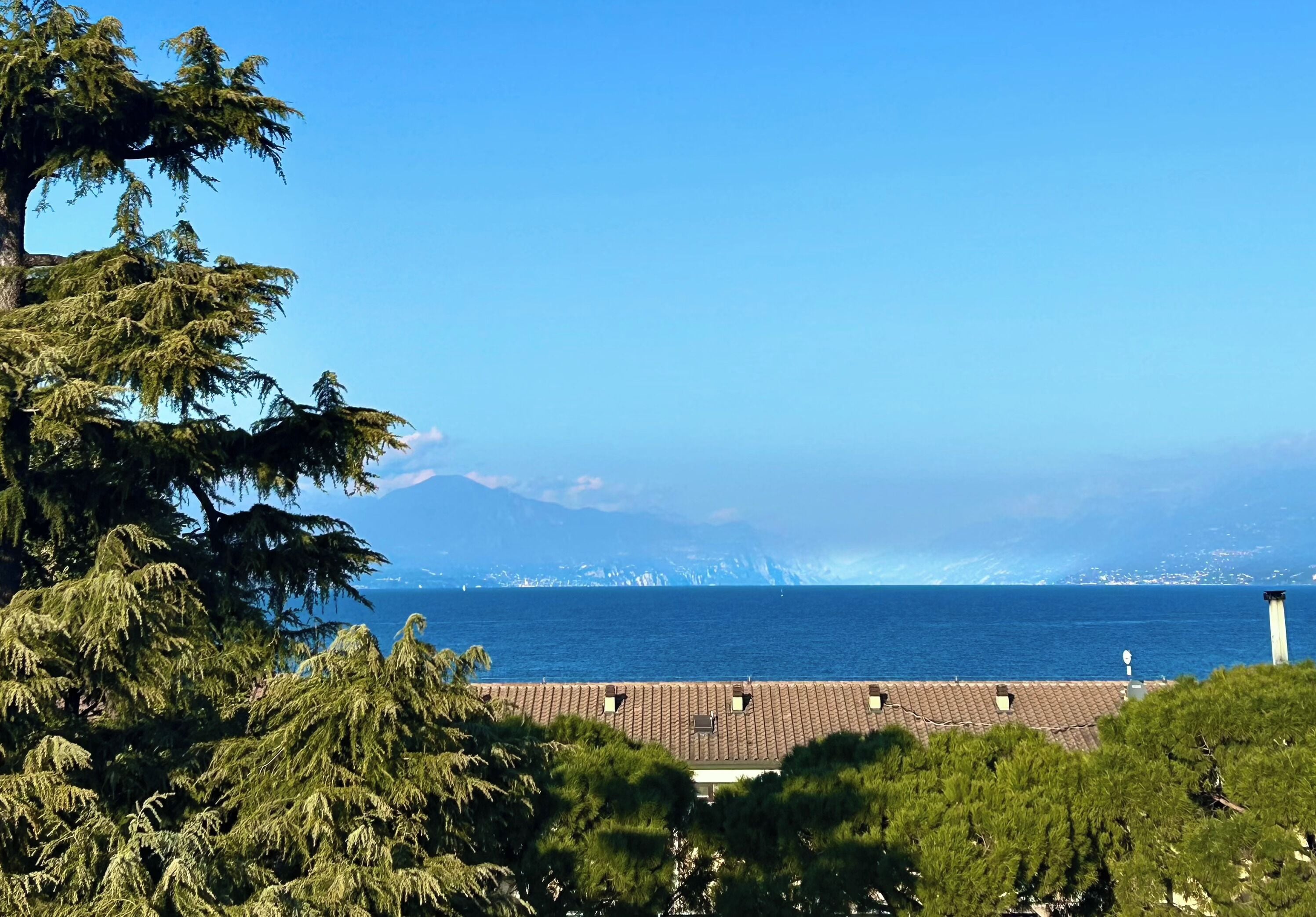 Une vue sur la côte, avec une montagne en arrière-plan, un ciel dégagé et un bâtiment doté d’un toit en tuiles.