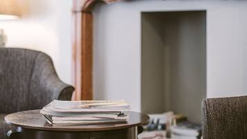 A room with a fireplace, a bookshelf, and a table with papers.