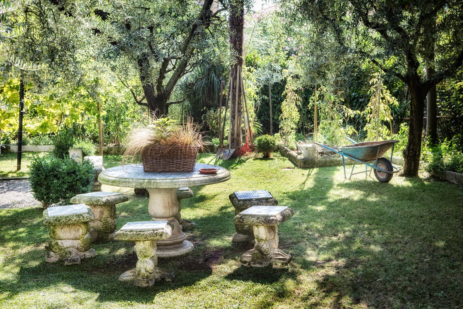 Ein Garten mit Steintisch, Schütte und einem kleinen Teich.