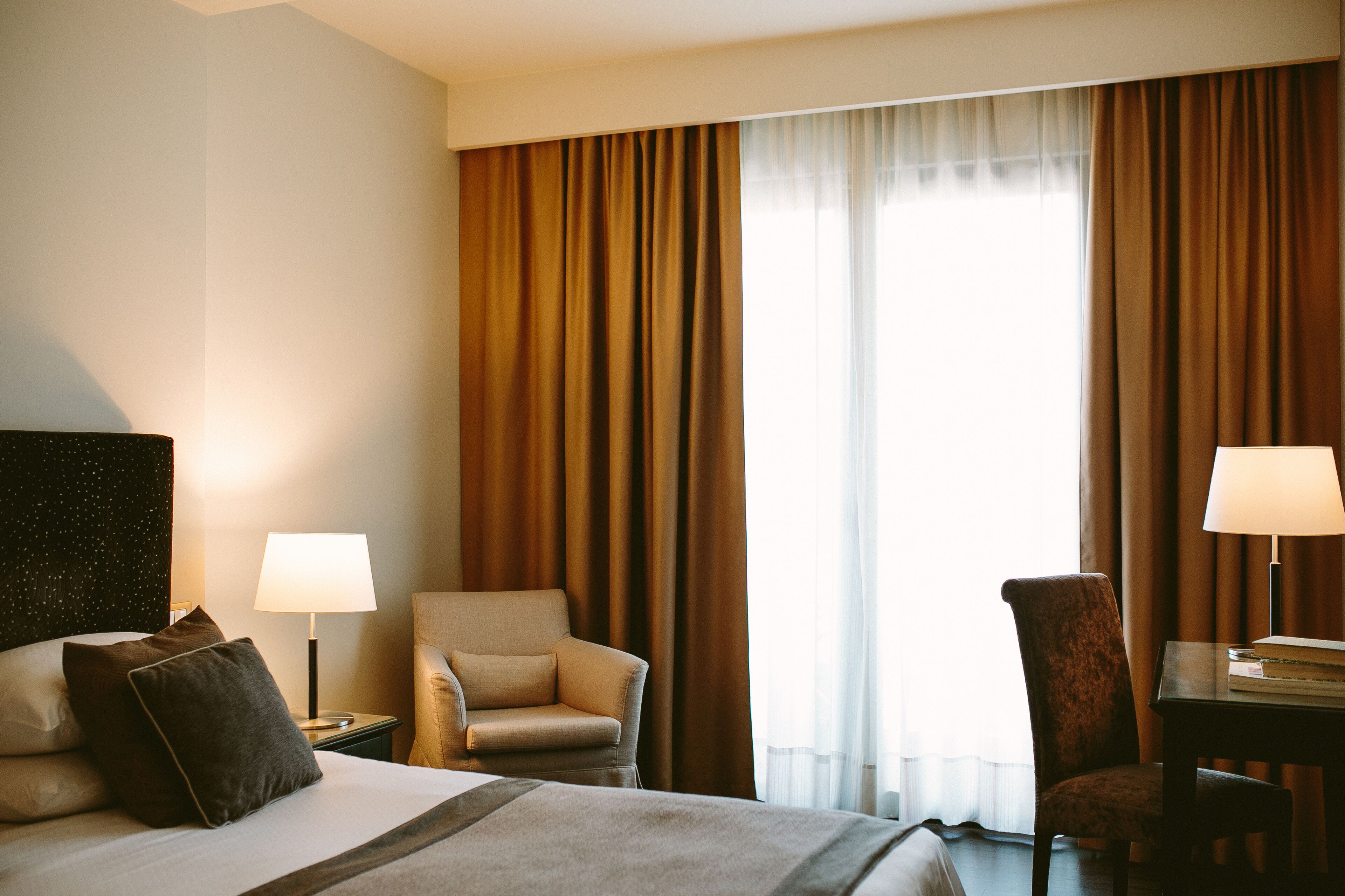 Ein Hotelzimmer mit einem Bett, zwei Stühlen, einem Schreibtisch und einer Lampe.