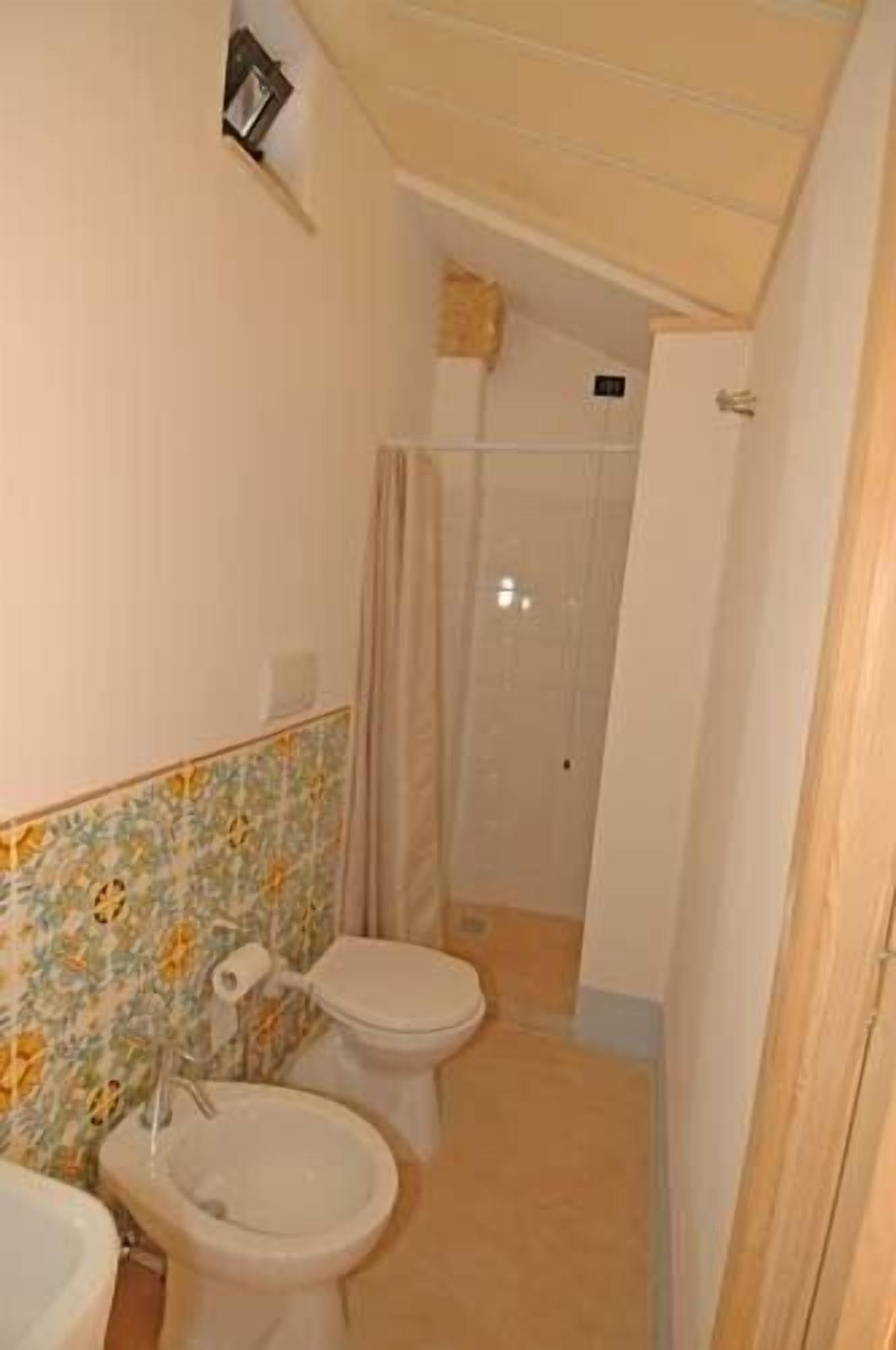 Une petite salle de bain avec deux toilettes, un lavabo et un espace douche.