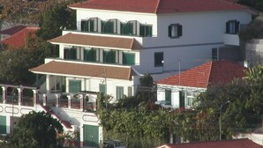 A multi-story building with a red-tiled roof, large windows, and a balcony. - Vila Marta (Funchal)