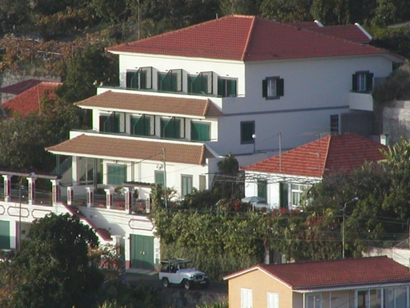 A multi-story building with a red-tiled roof, large windows, and a balcony.
