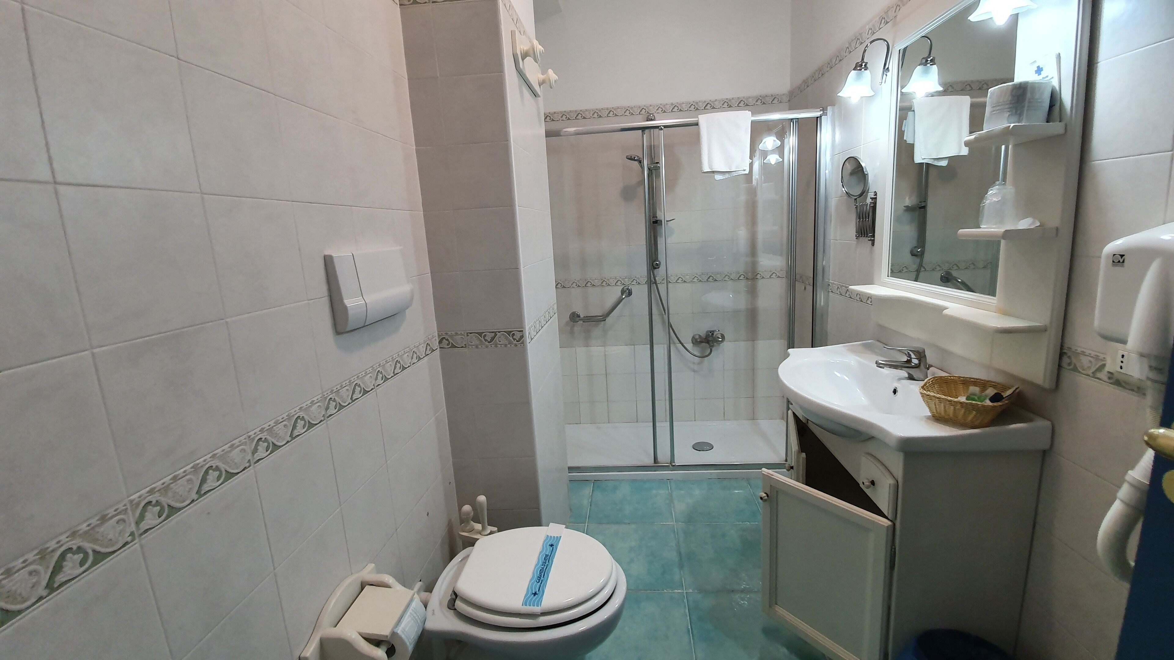 Ein Badezimmer mit Toilette, Waschbecken, Dusche und Spiegel.