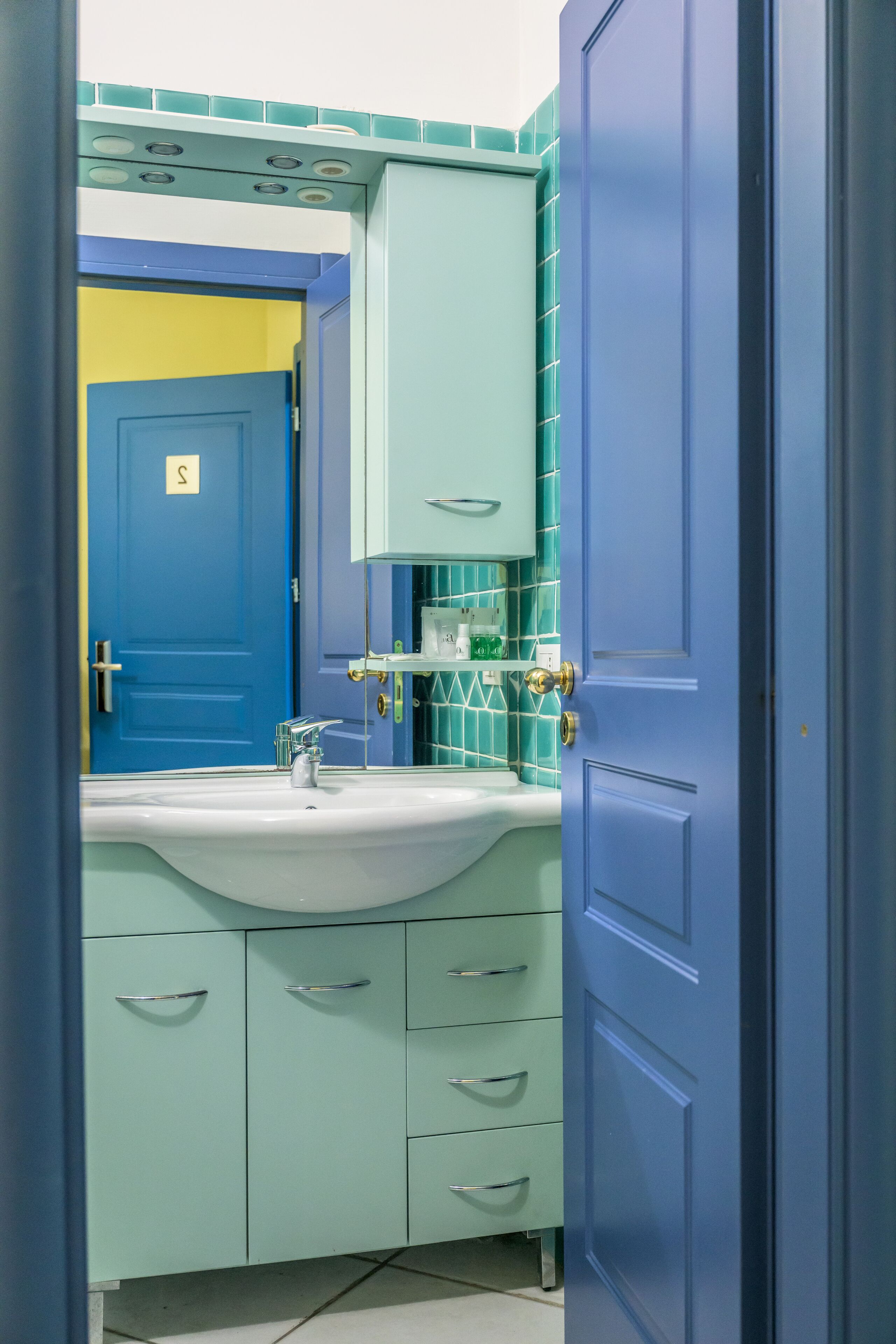 A bathroom with a blue door, a sink, and a mirror.