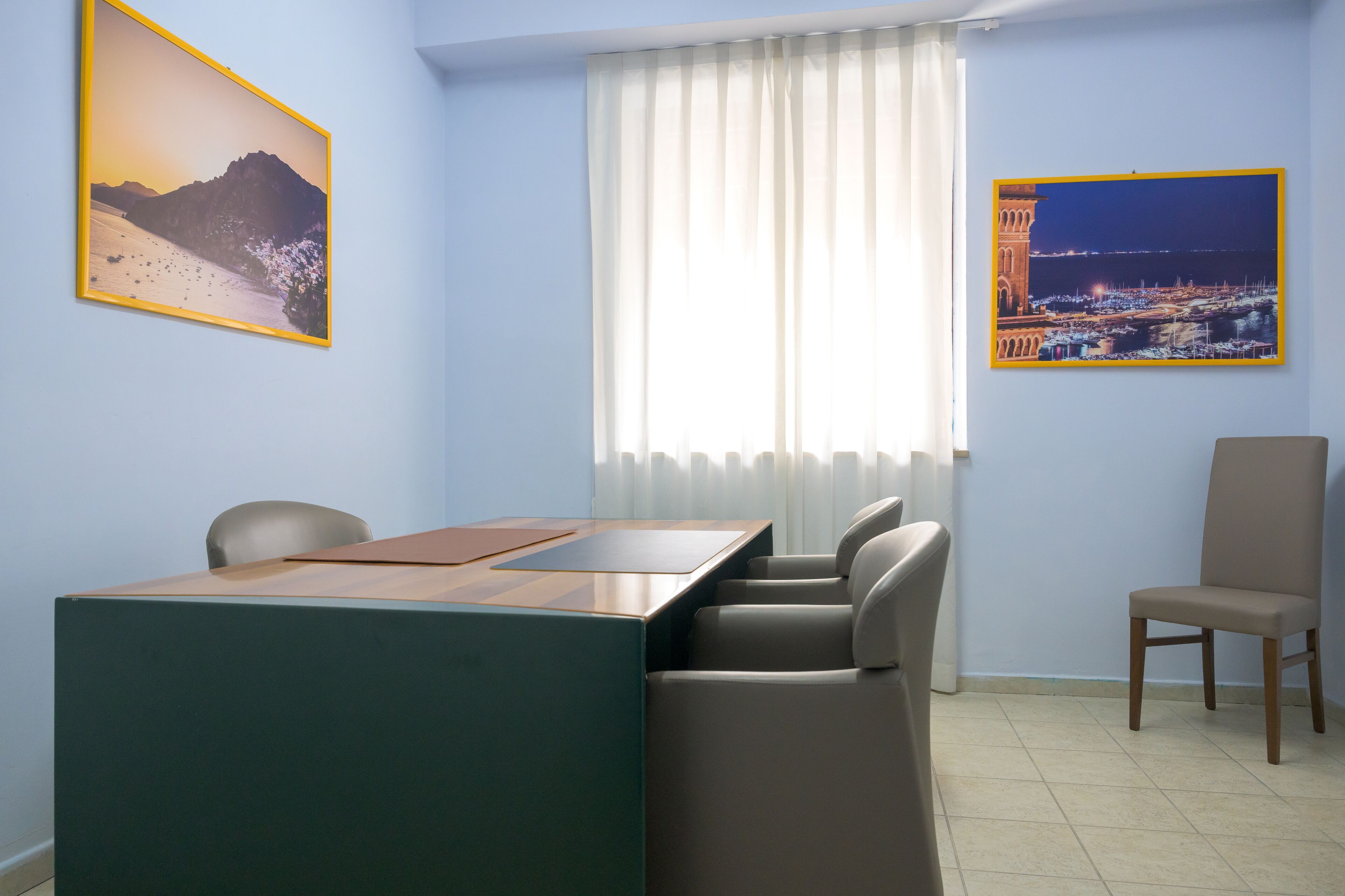 A conference room with a table, chairs, and two framed pictures on the walls.