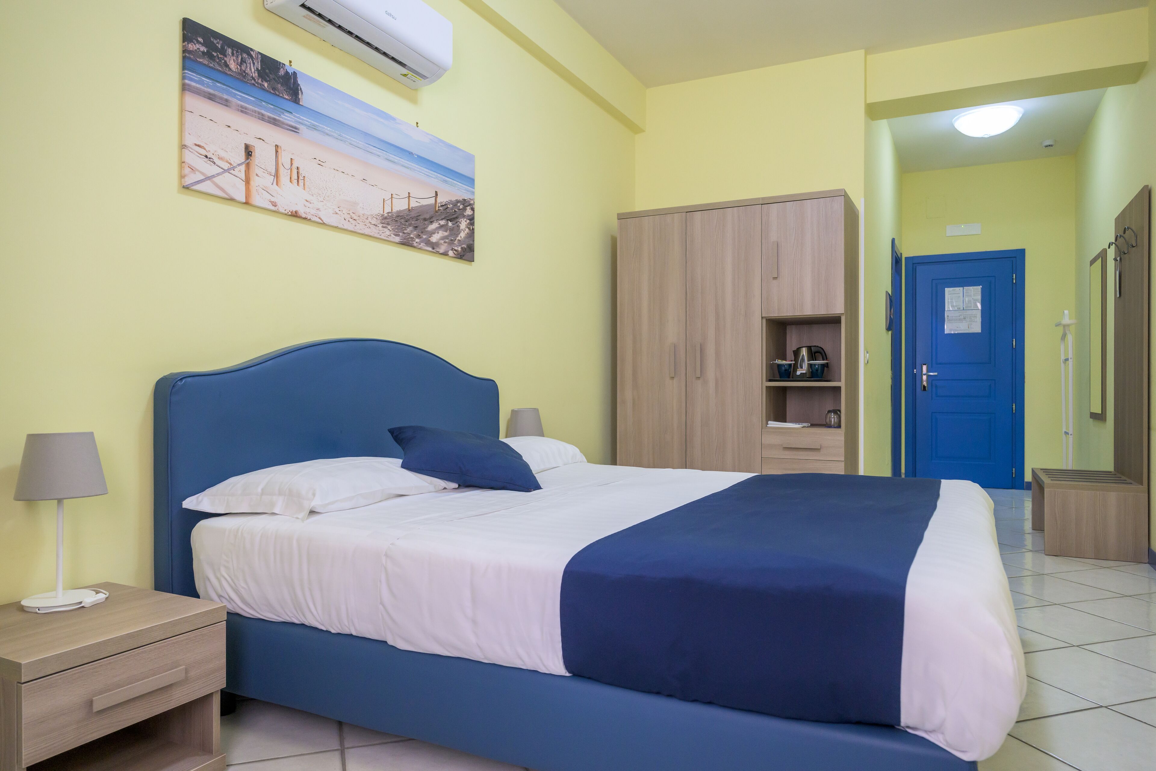 Un dormitorio ordenado con cama, mesitas de noche, un armario y un cuadro en la pared.