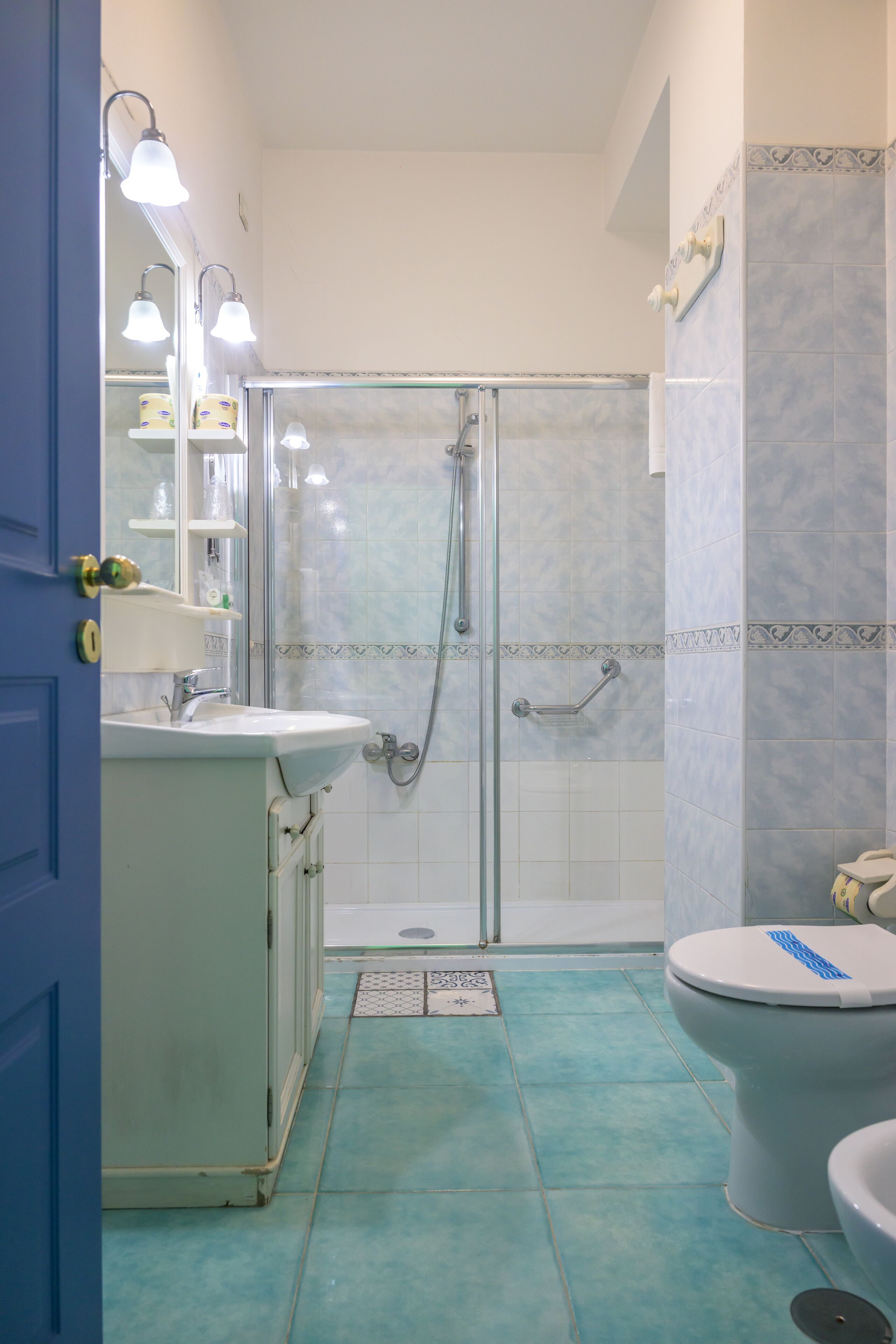 A bathroom with a glass-enclosed shower, a sink with a mirror, and a toilet.