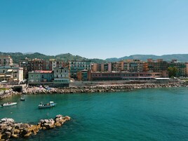 Un pueblo costero con edificios coloridos, una costa rocosa y barcos en el agua.