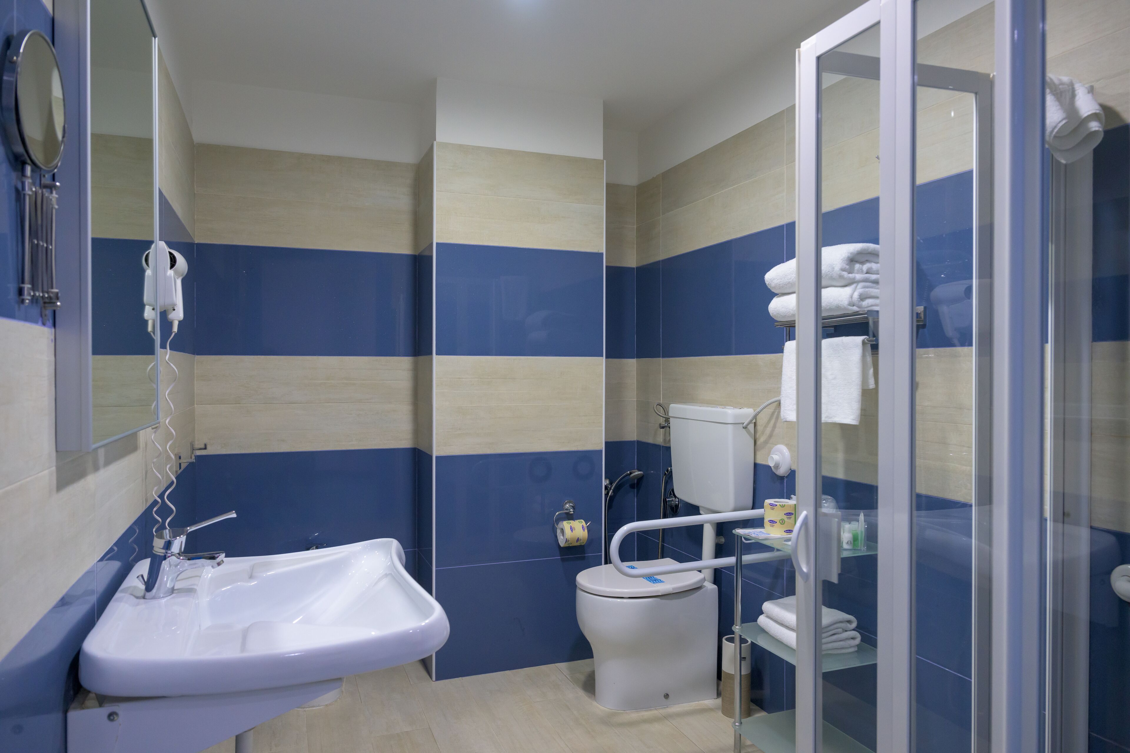 A bathroom with a sink, toilet, and glass shower enclosure.