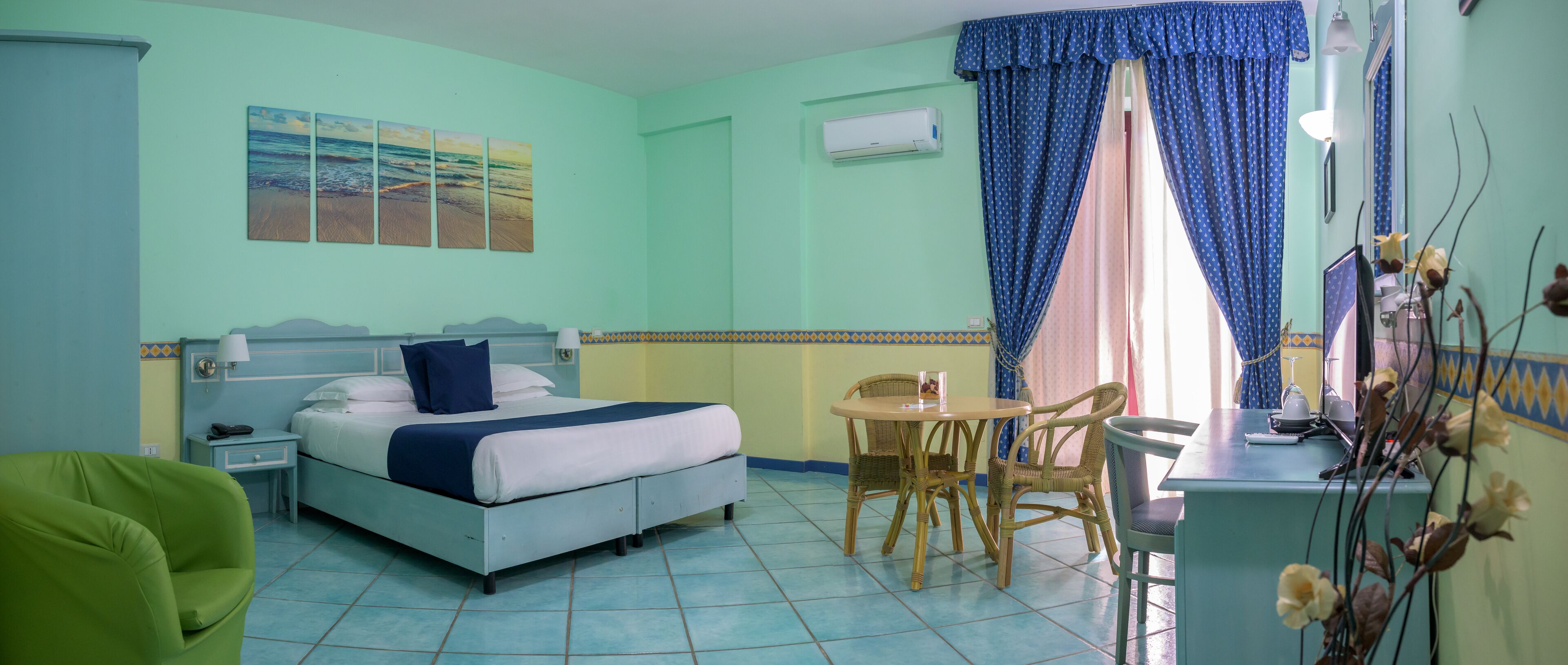 A hotel room with a bed, a desk, a chair, and a small table.