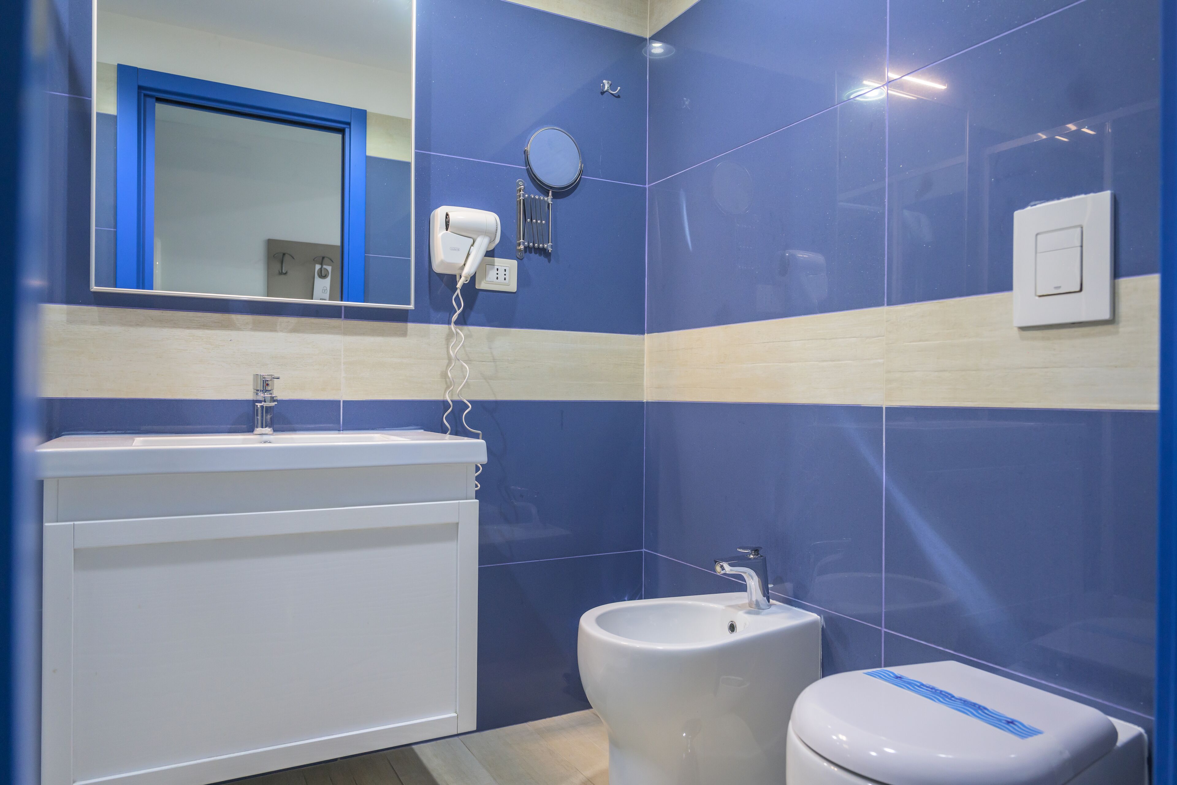 A bathroom with a white sink, a bidet, and a mirror.