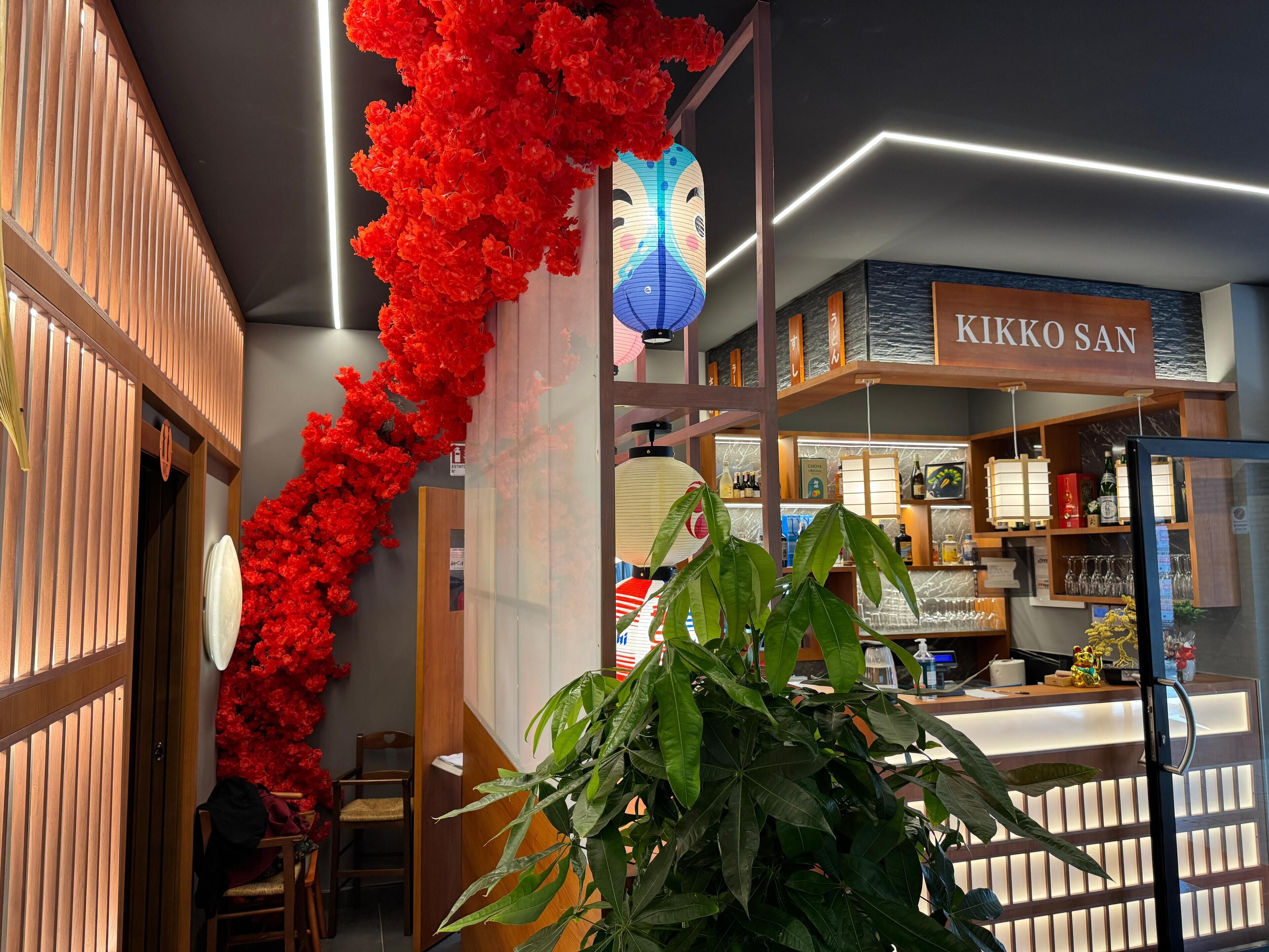 Un interior moderno con un mostrador de recepción, paneles de madera y un cartel que dice "KIKKO SAN".