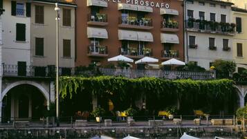 A hotel with a sign reading "HOTEL PIROSCAFO" and a waterfront view with boats docked.
