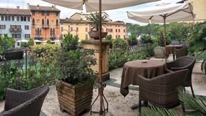 Un patio al aire libre con mobiliario de mimbre, una mesa con mantel y plantas en macetas.