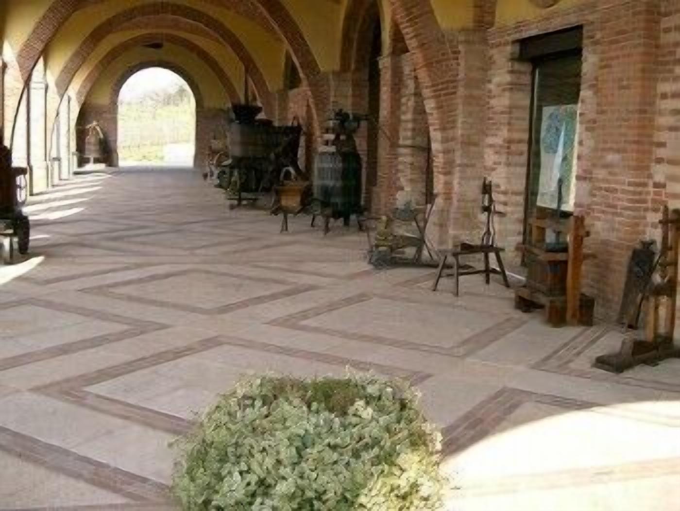 A corridor with arched ceilings and tiled flooring, leading to a room with a fireplace and various items on shelves.