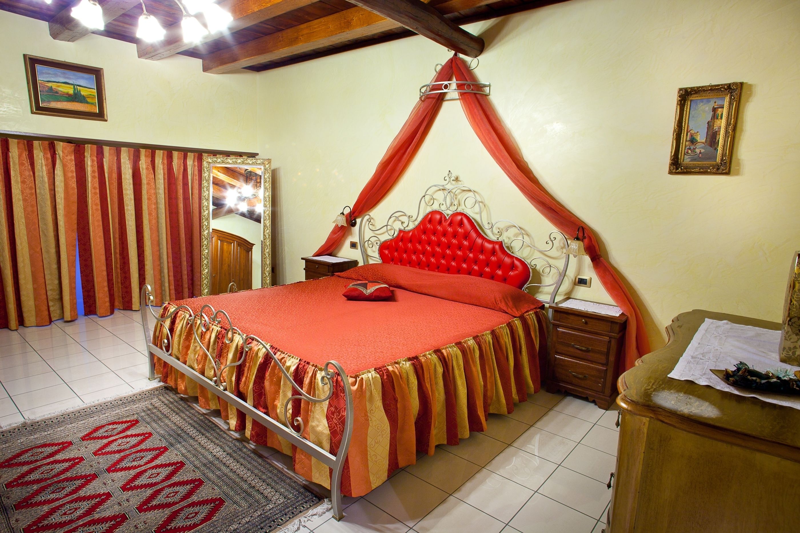 A bedroom with a four-poster bed, a wooden nightstand, a dresser, and a patterned rug.