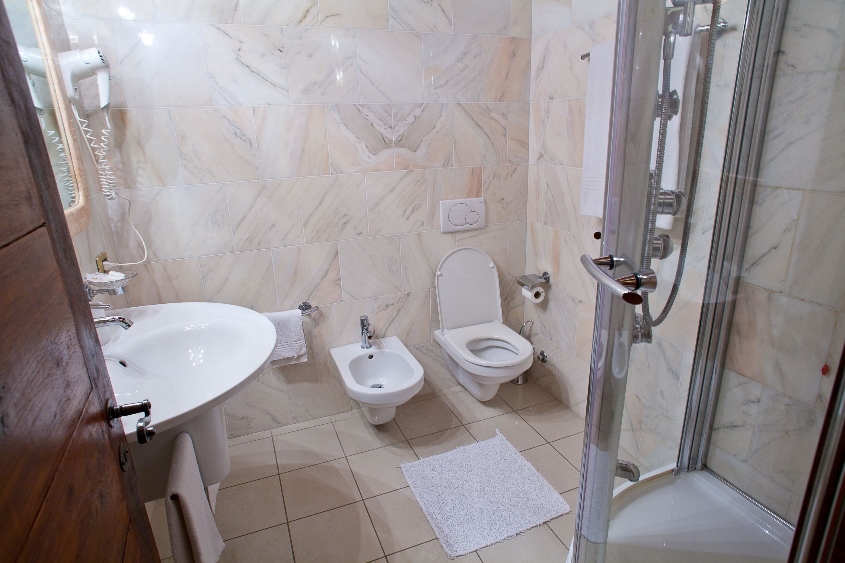 A bathroom with a sink, bidet, toilet, and glass-enclosed shower.