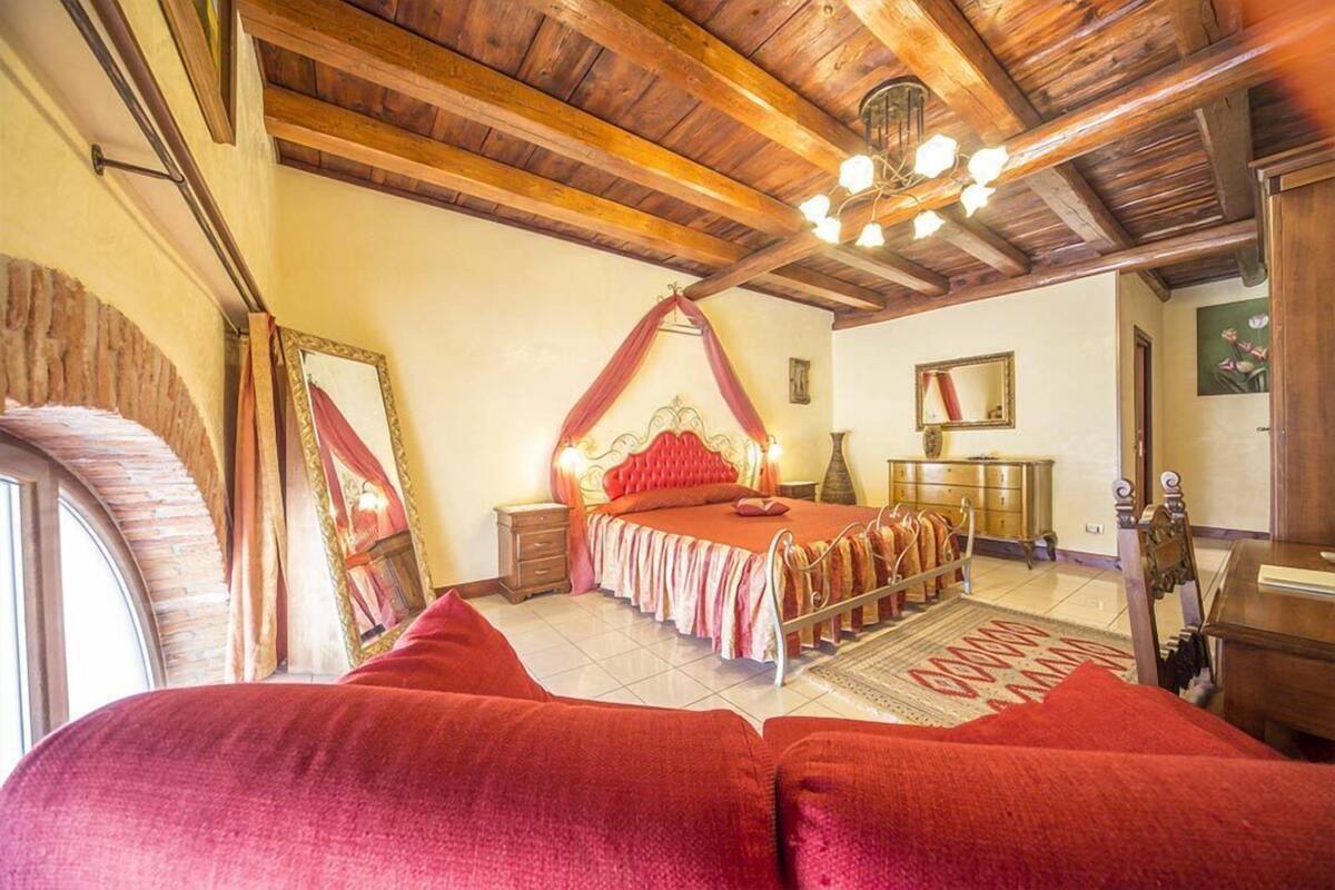 Une chambre avec un plafond en bois, un lit à baldaquin, un miroir et une commode.