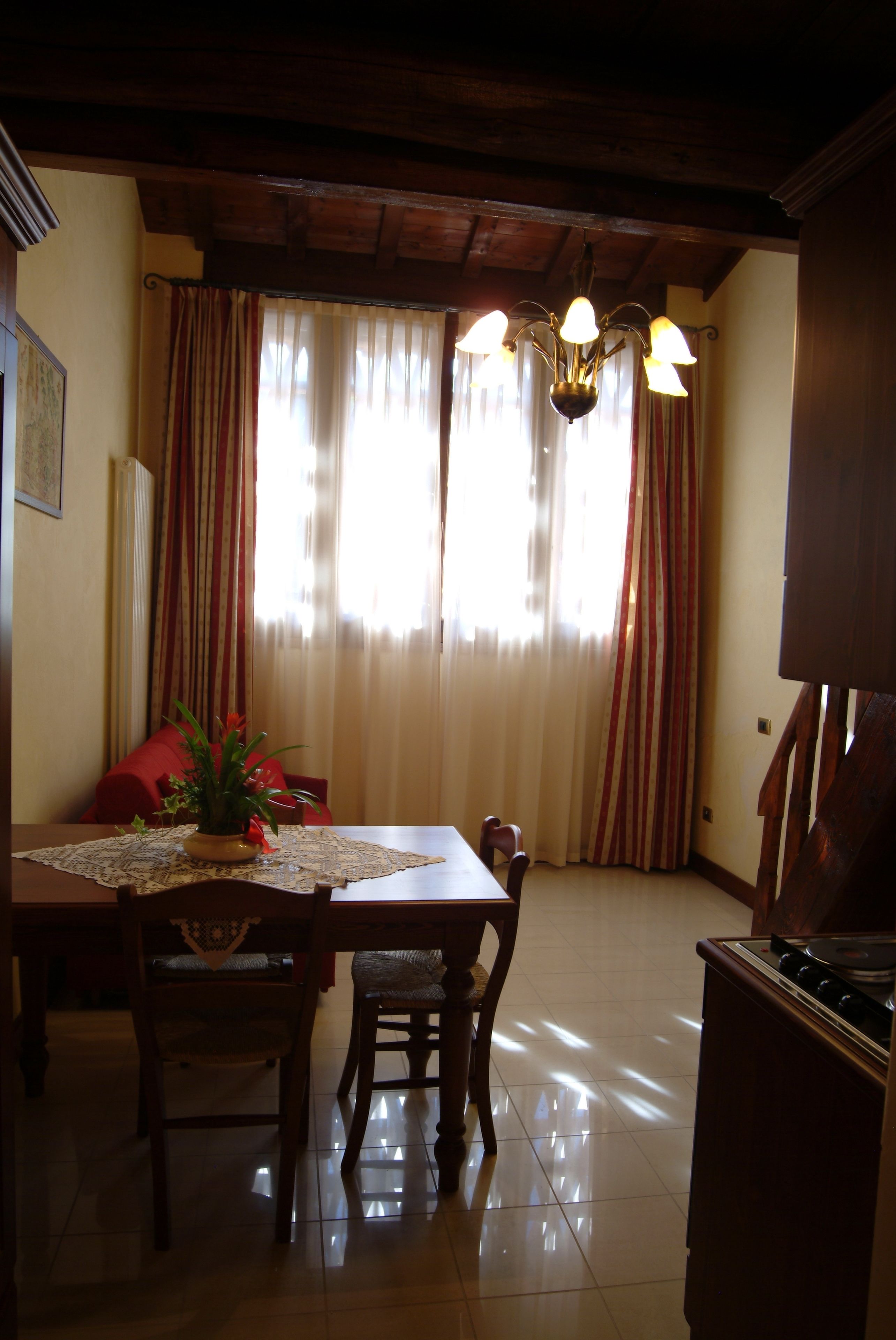A dining area with a wooden table, chairs, a chandelier, and curtains.