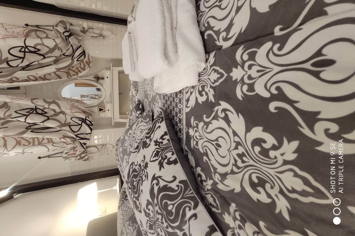 A bathroom with a white vanity, a mirror, and a towel hanging on the wall.