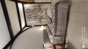 Una habitación con techo curvo, un sofá estampado y una pared con diseños abstractos.