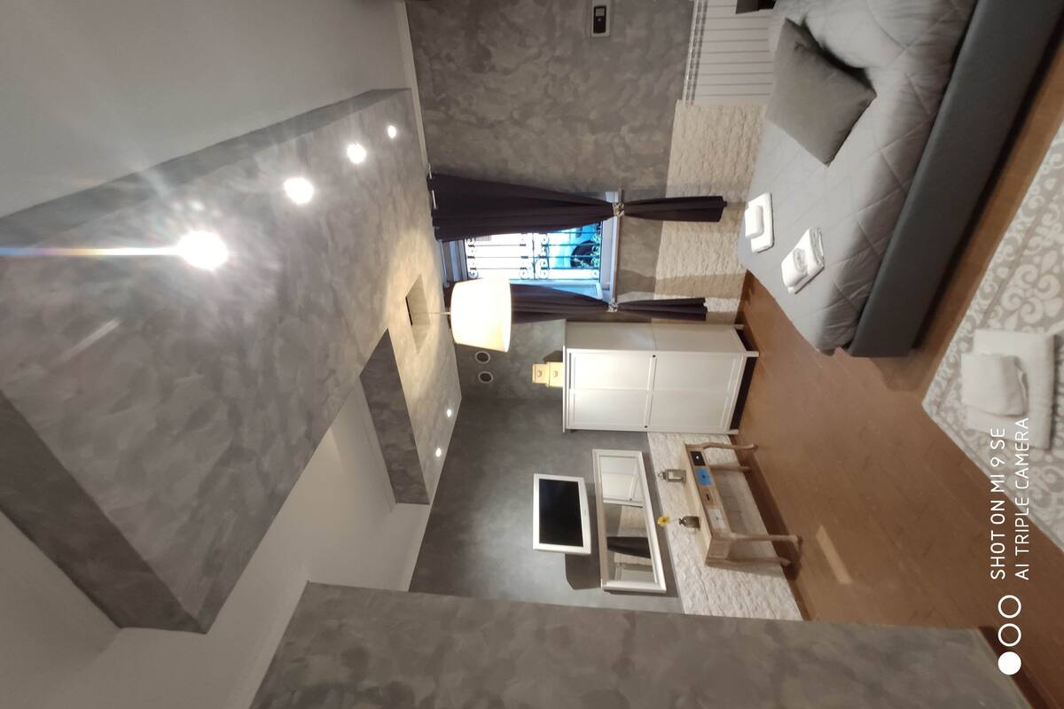 A modern hotel room with a large bed, a desk, and a bathroom.
