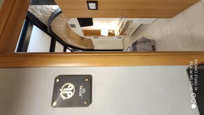 Habitación de hotel con techo de madera, unidad de aire acondicionado visible, un pequeño cuadro enmarcado en la pared y un cartel que indica el número de habitación 101.