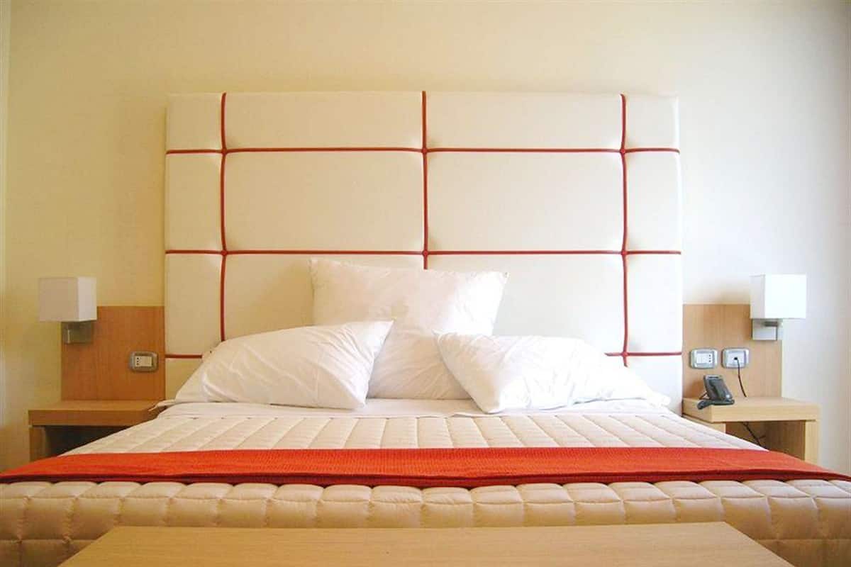 A hotel room with a large bed, two bedside tables, and a wooden nightstand.